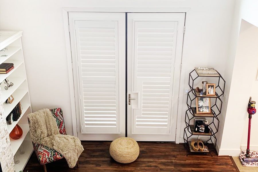 White plantation shutter customized for French door with cutout for handle.