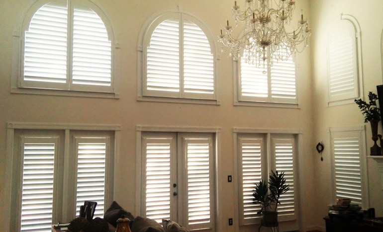 TV room in two-story Clearwater home with plantation shutters on high ceiling windows.